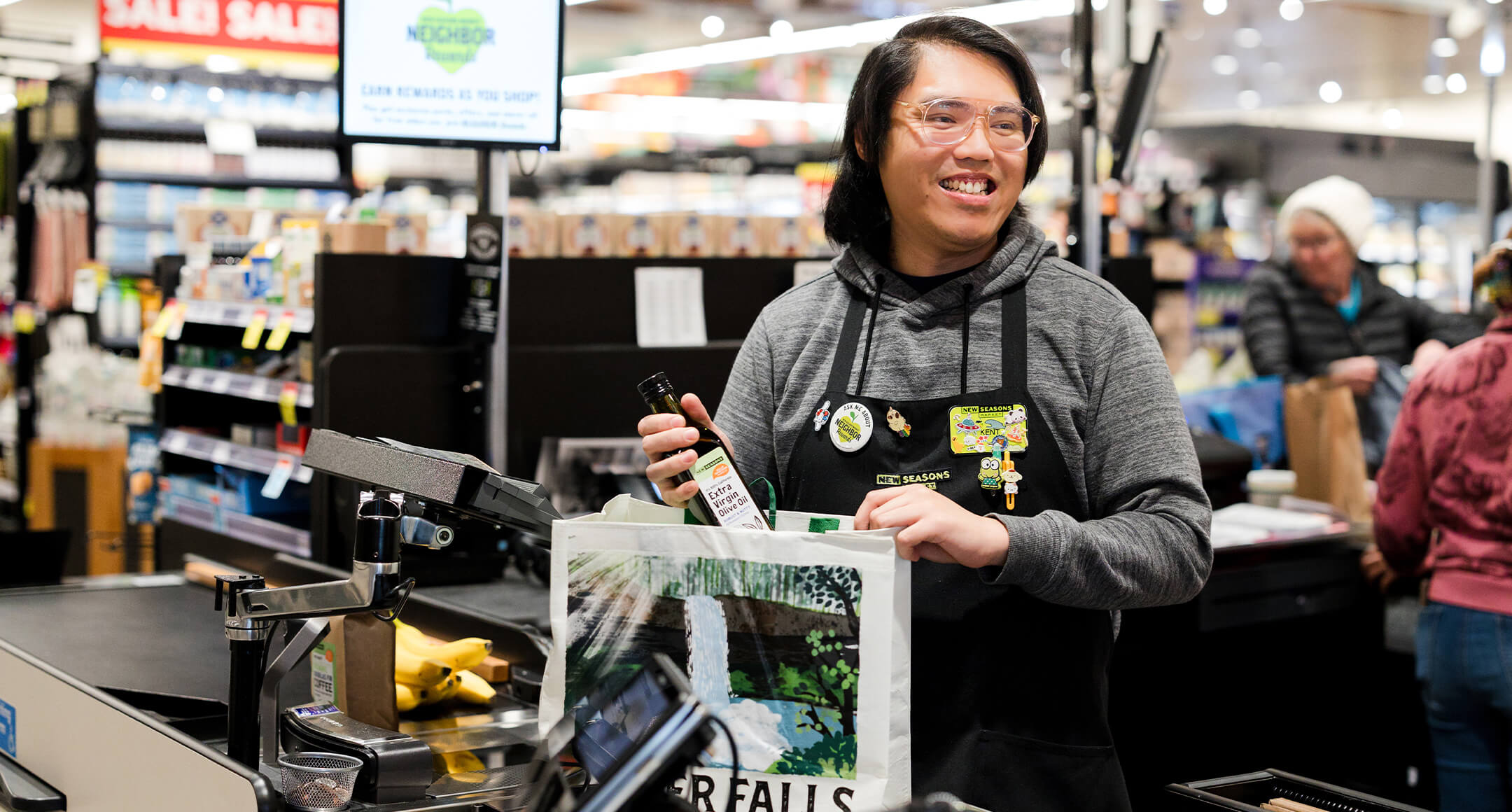 A New Seasons Market team member bagging groceries at the register.