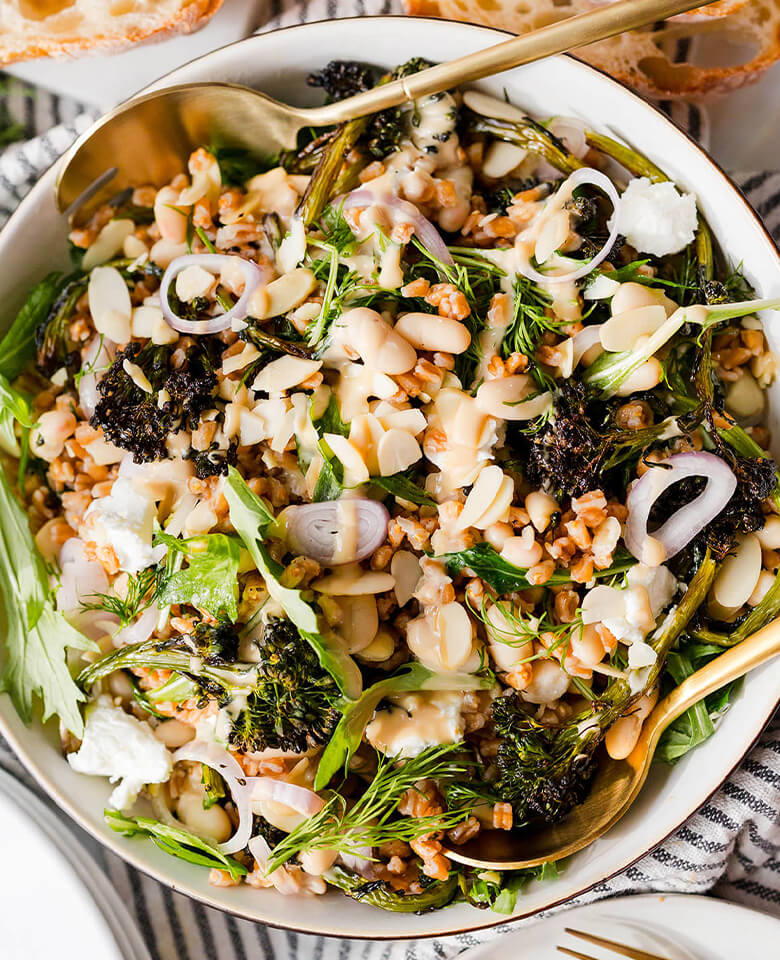 Hearty farro salad with white beans, roasted broccoli, and lemon-tahini dressing served in a bowl.