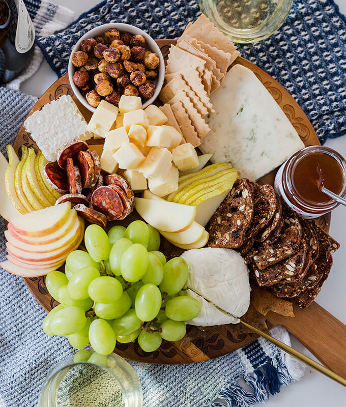 a cheese board with fruit, nuts, cheeses and more!