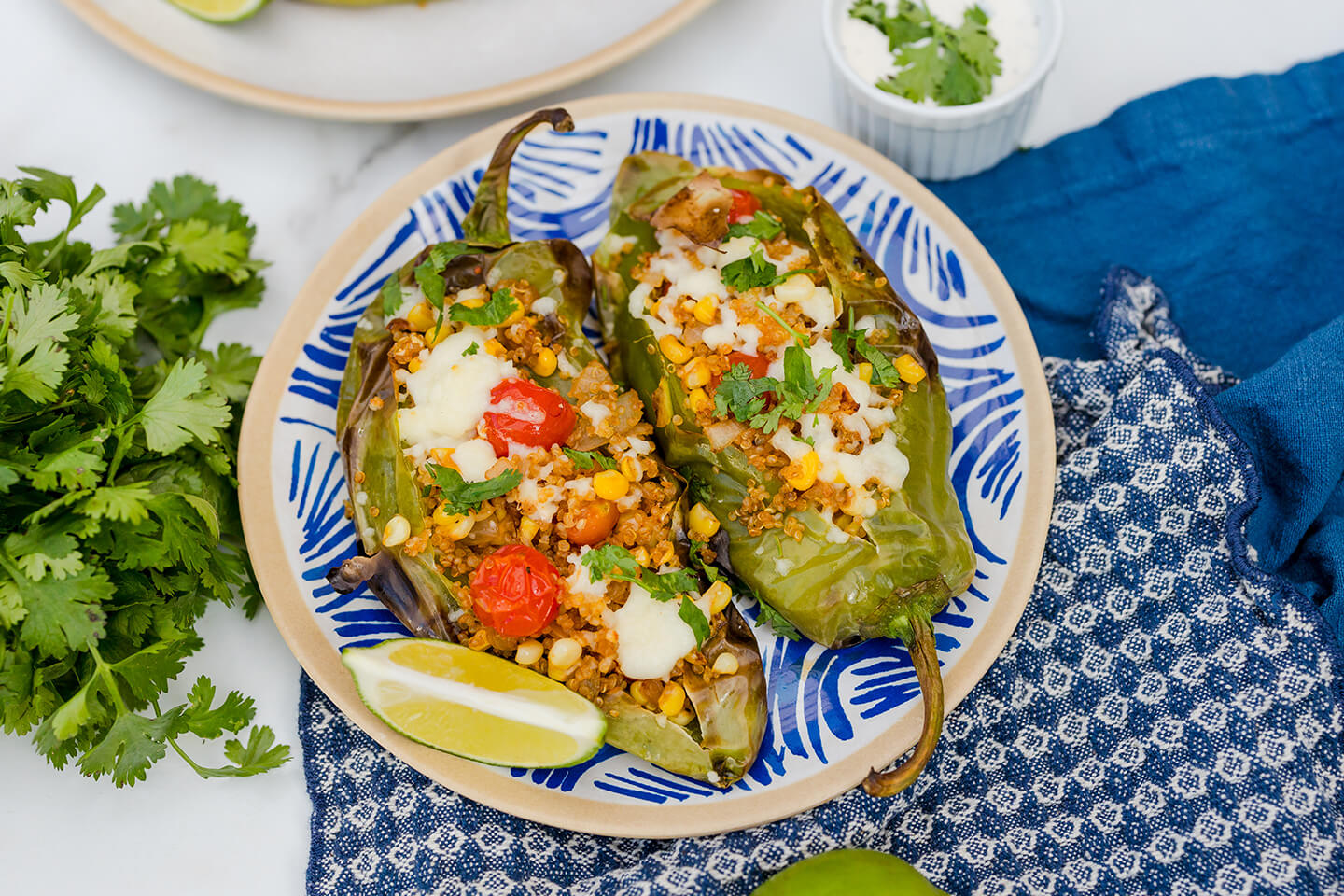 A plate with two stuffed Hatch chiles topped with melted cheese and sliced cherry tomatoes. 