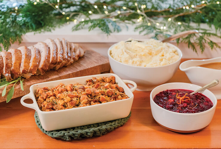 A holiday table set with roasted turkey and traditional sides. 