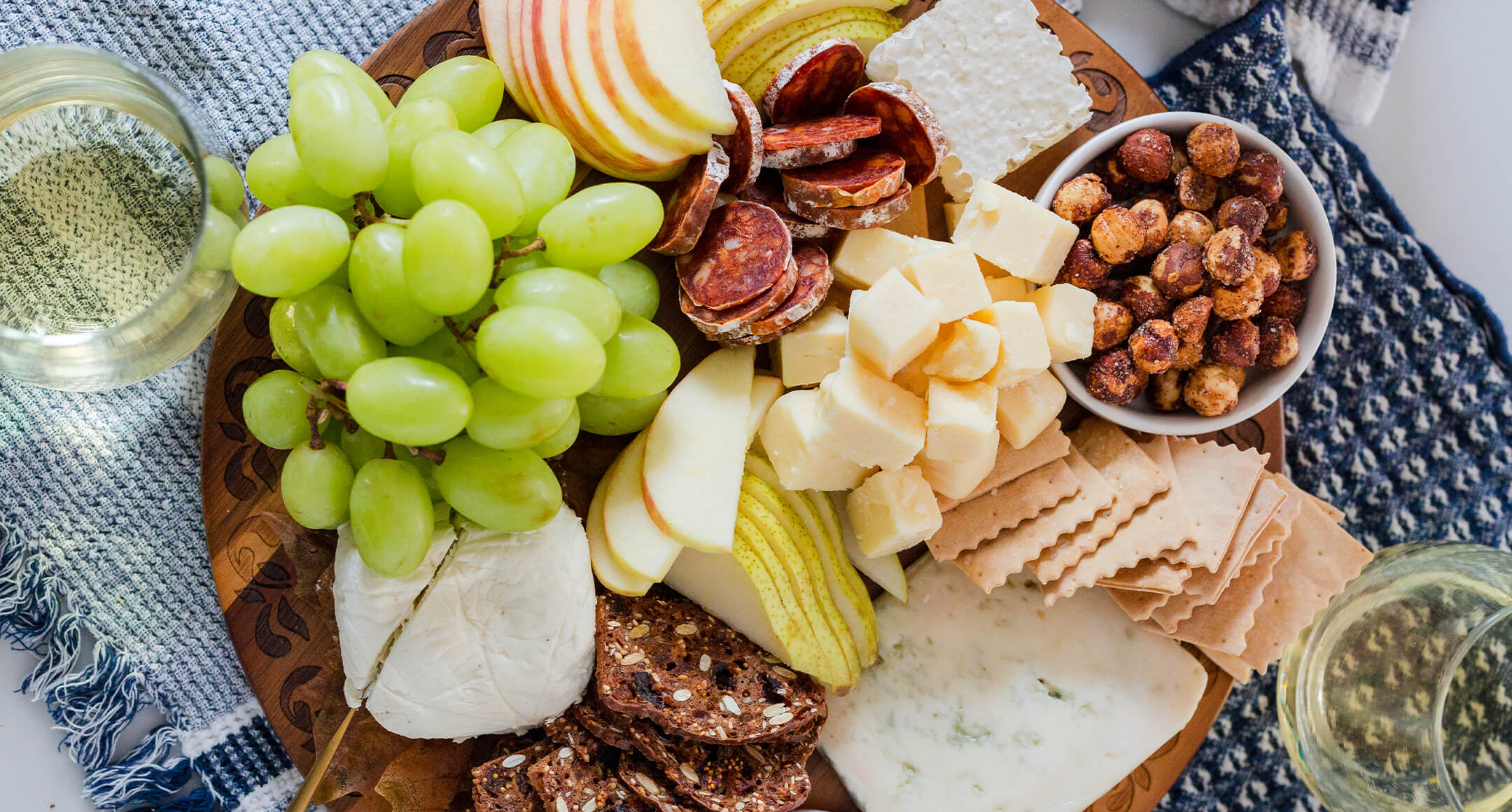 A cheese board with cubed and sliced Oregon cheese, nuts, grapes, and other sliced fruit. 