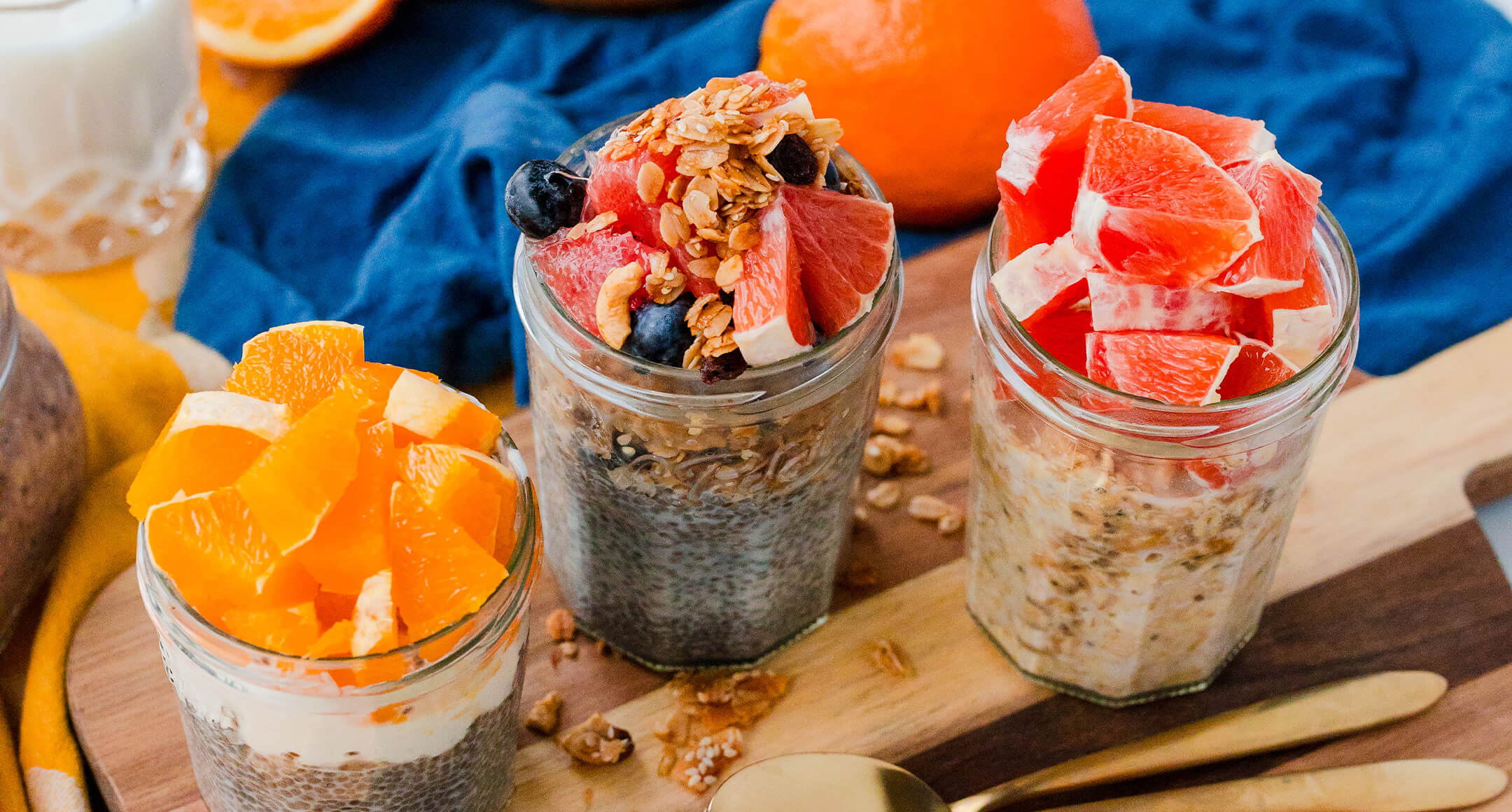 Three jars of overnight oats and chia pudding topped with fresh fruit.