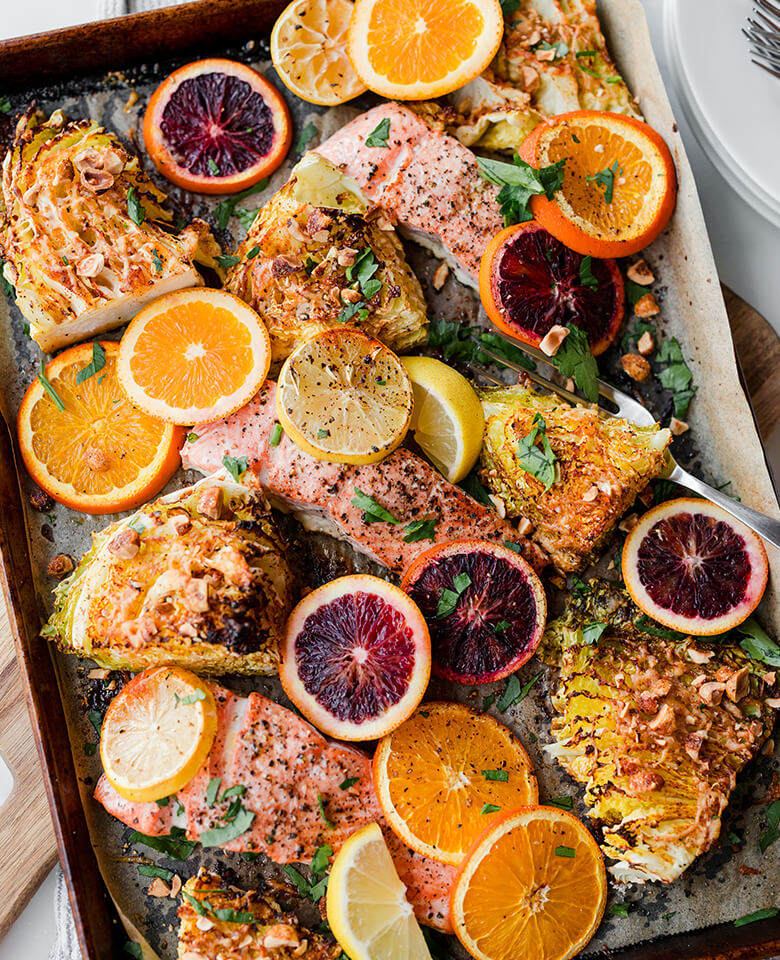 Sheet-pan salmon baked and served with orange slices.