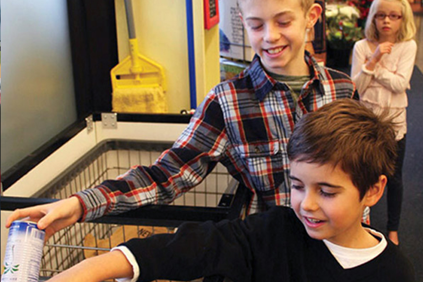 Three children donating recyclable cans for Cans for Kids donations.