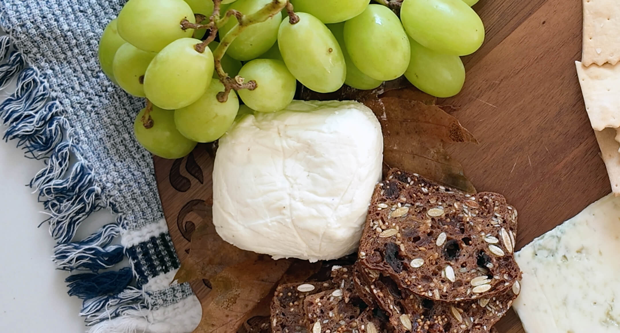 A cheese board featuring River’s Edge Chevre with crackers and grapes. 