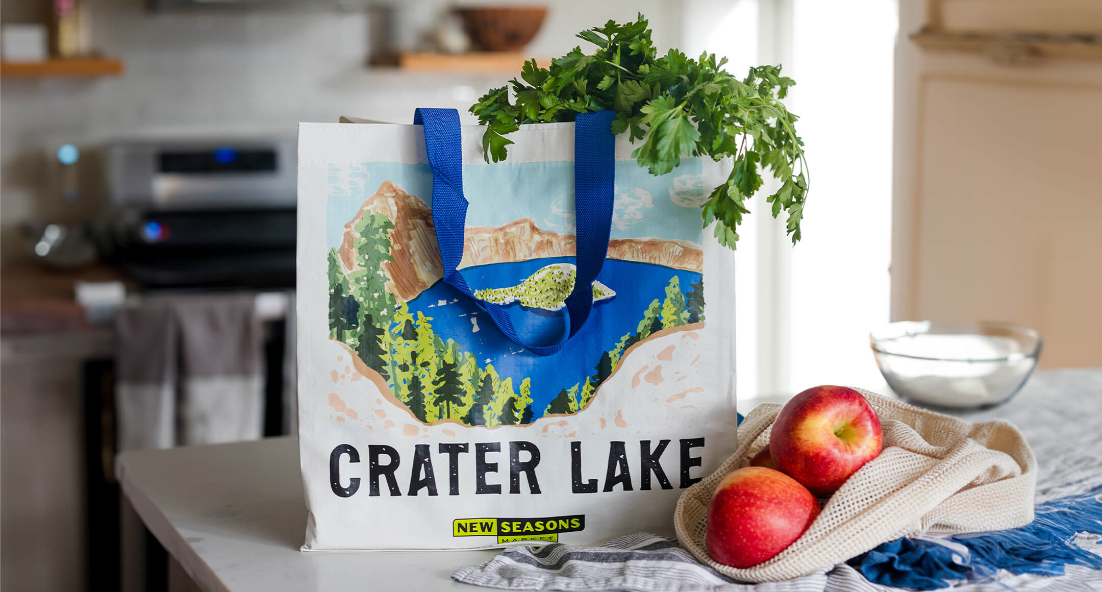 A New Seasons Market limited-edition reusable grocery bag featuring an artistic rendering of Crater Lake.