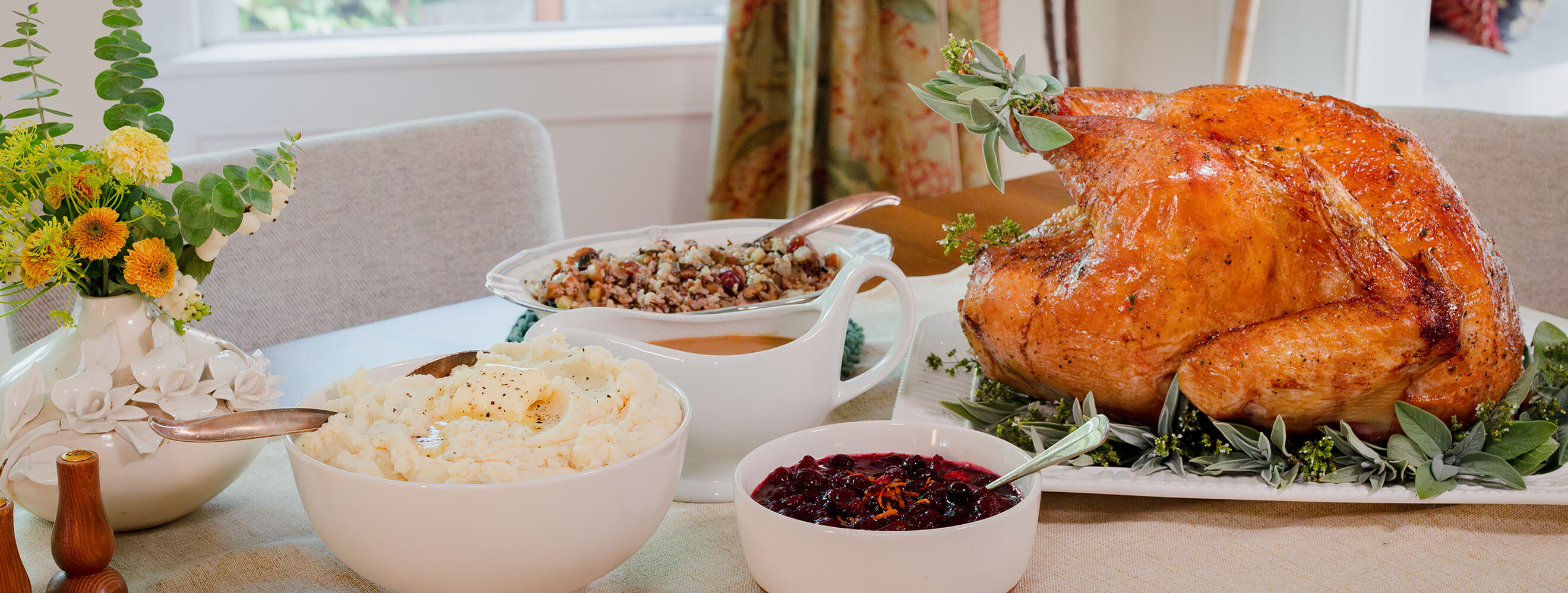 An oven-roasted turkey on a platter with a bowl of cranberry sauce on the side.