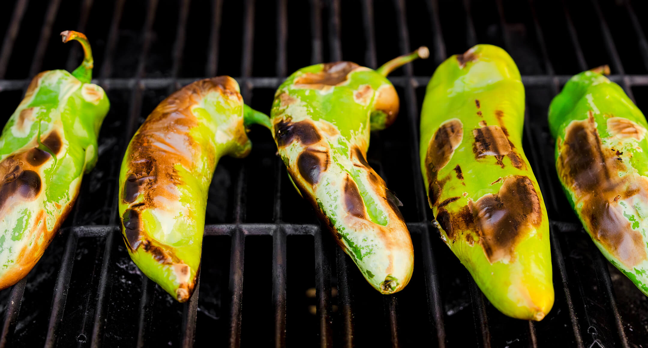 Charred hatch chiles on a grill. 