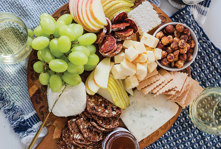 Cheese board with grapes, nuts, cheeses, apples and wine