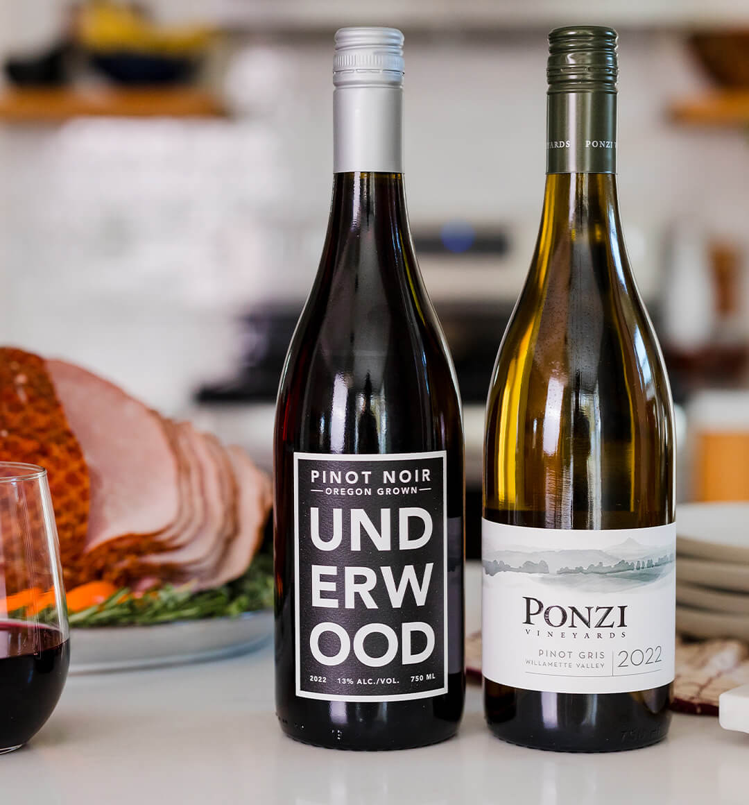 A cropped image of a bottle of white wine from Ponzi Vineyards on a tabletop next to a class of wine.