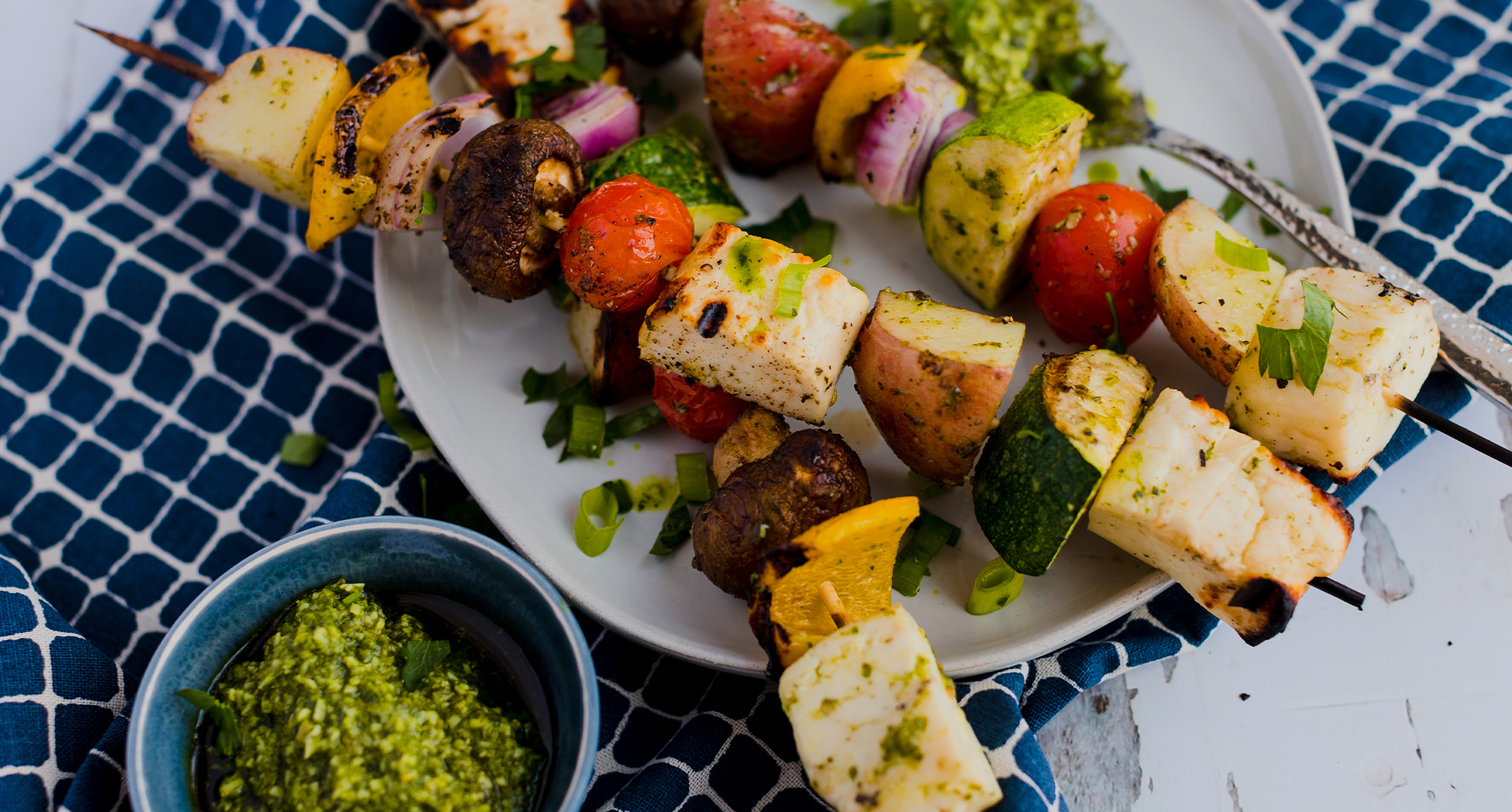 Grilled halloumi cheese and veggies skewers on a plate. 