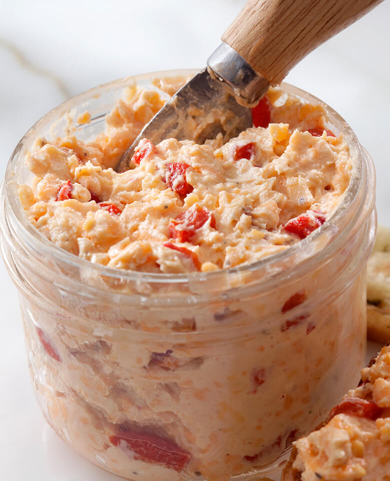 A serving of sweet & spicy pimento cheese spread in a glass jar.