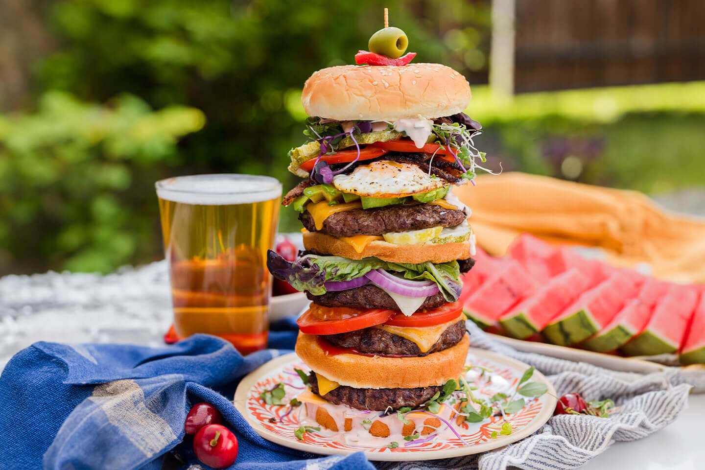 a gigantic burger stacked high with multiple beef patties and layers of cheese, egg, tomato and more!