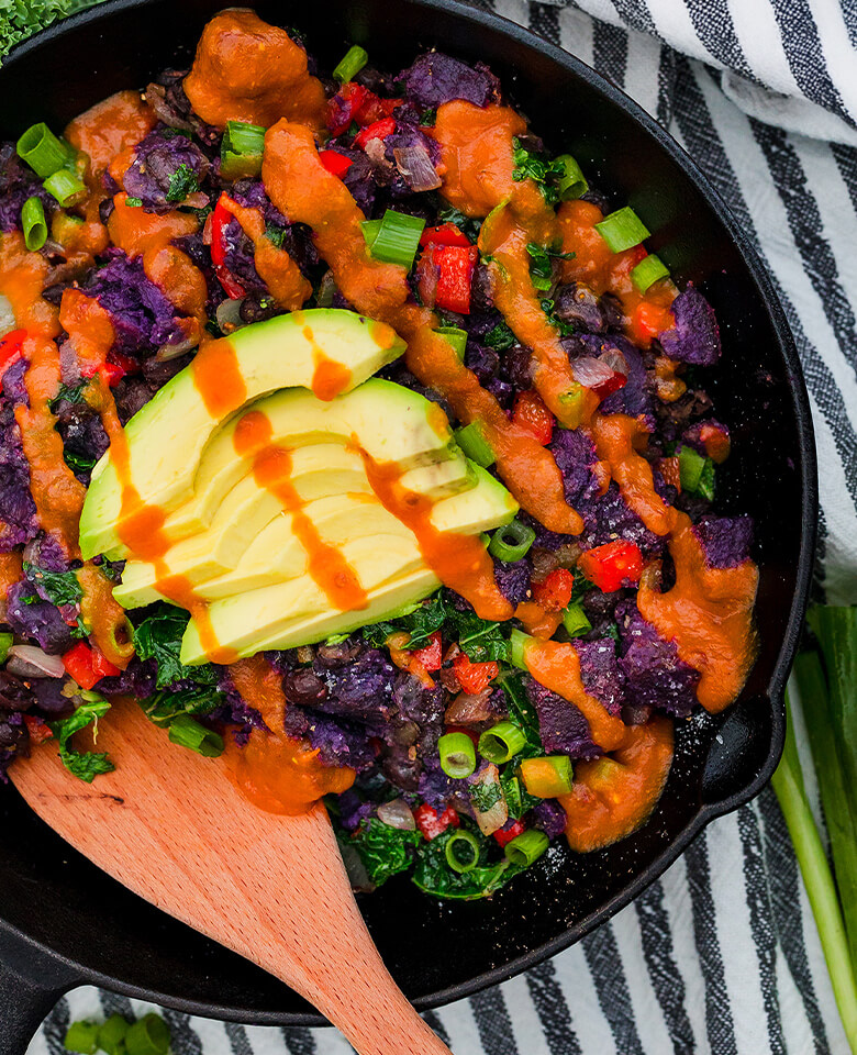 Chipotle Sweet Potato and Black Bean Hash topped with sliced avocado and Plant Bomb Caribbean Peppa Sauce.