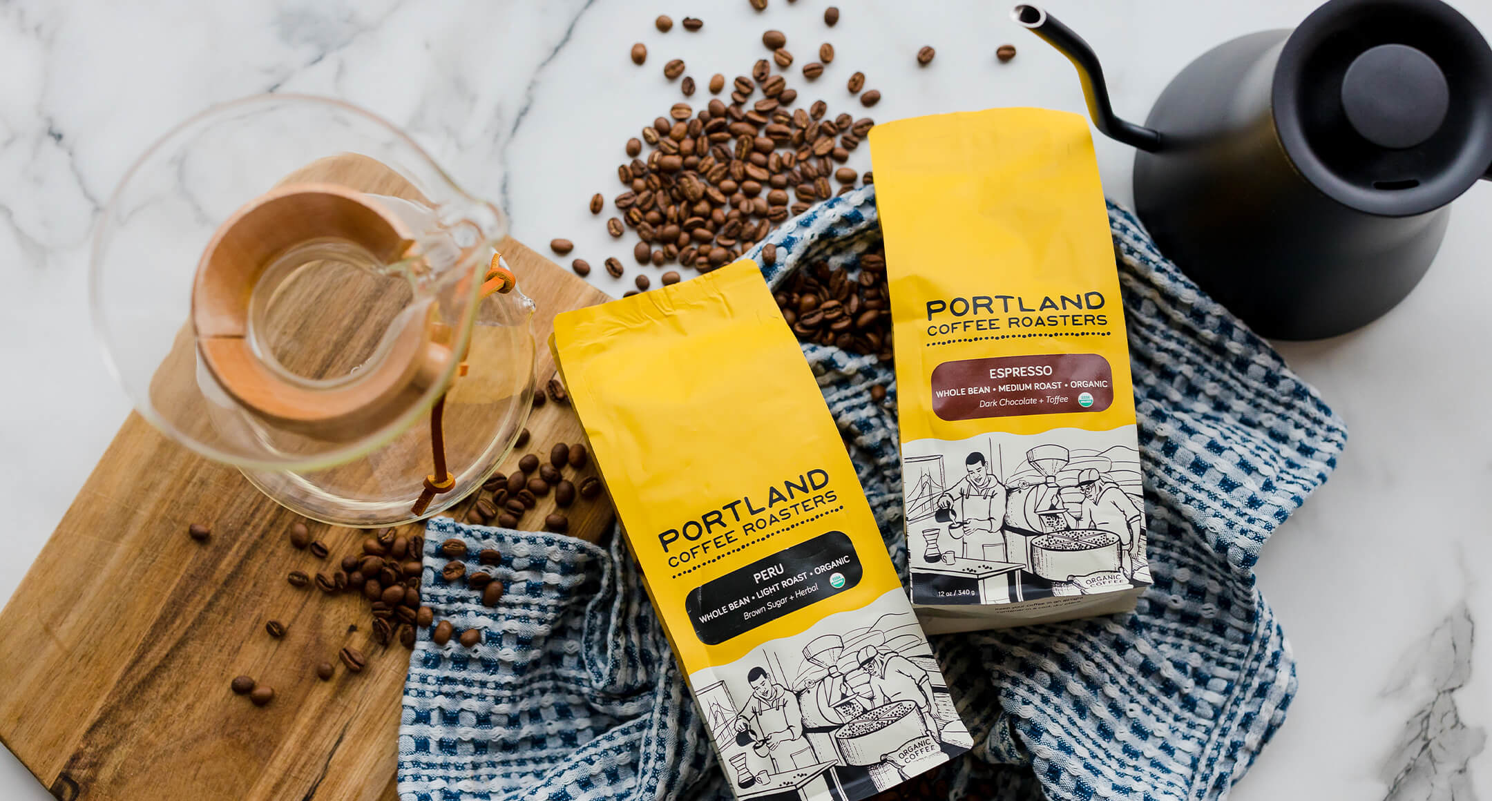 Two bags of organic coffee from Portland Roasting Company next to a Chemex brewer. 