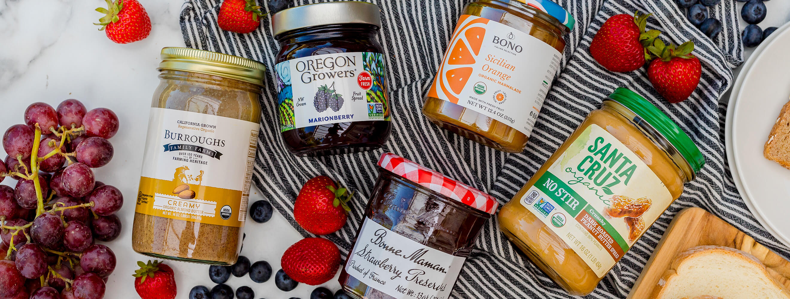 jars of nut butter and jams arranged on a towel with berries