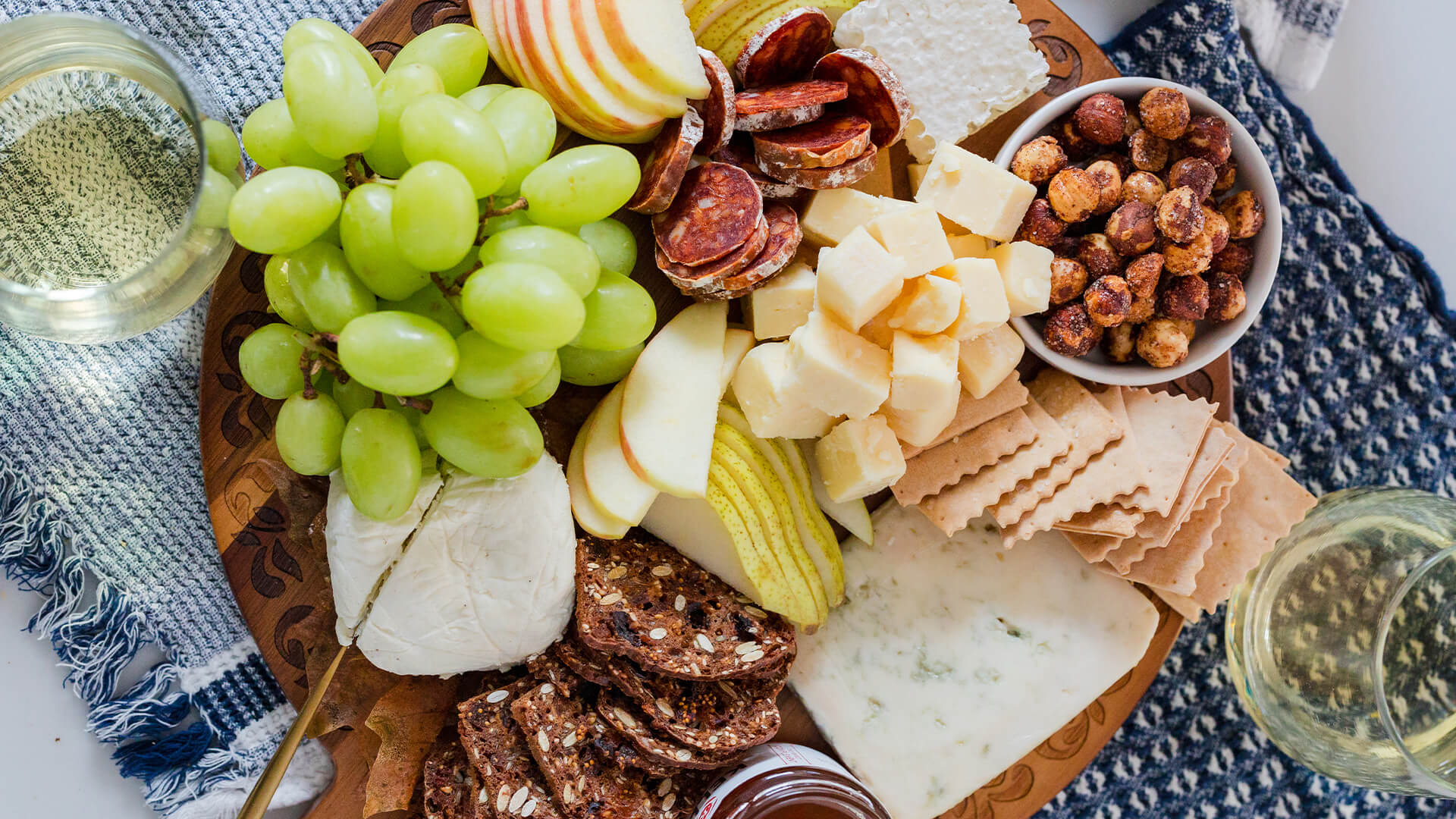 A charcuterie board of local cheeses, green grapes, pear slices, and crackers.