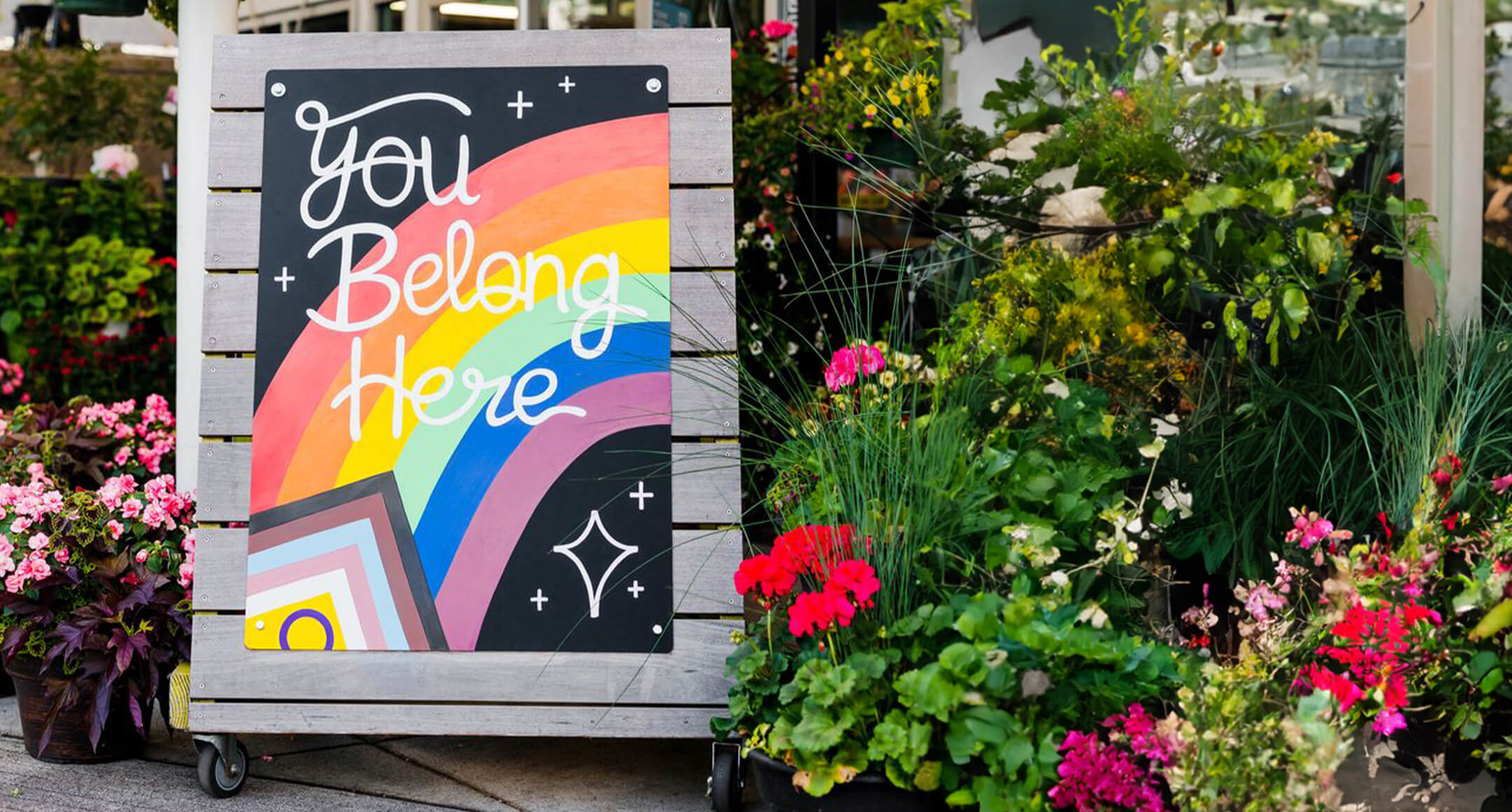 A hand-painted Pride Month sign outside of New Seasons Market that reads: You Belong Here