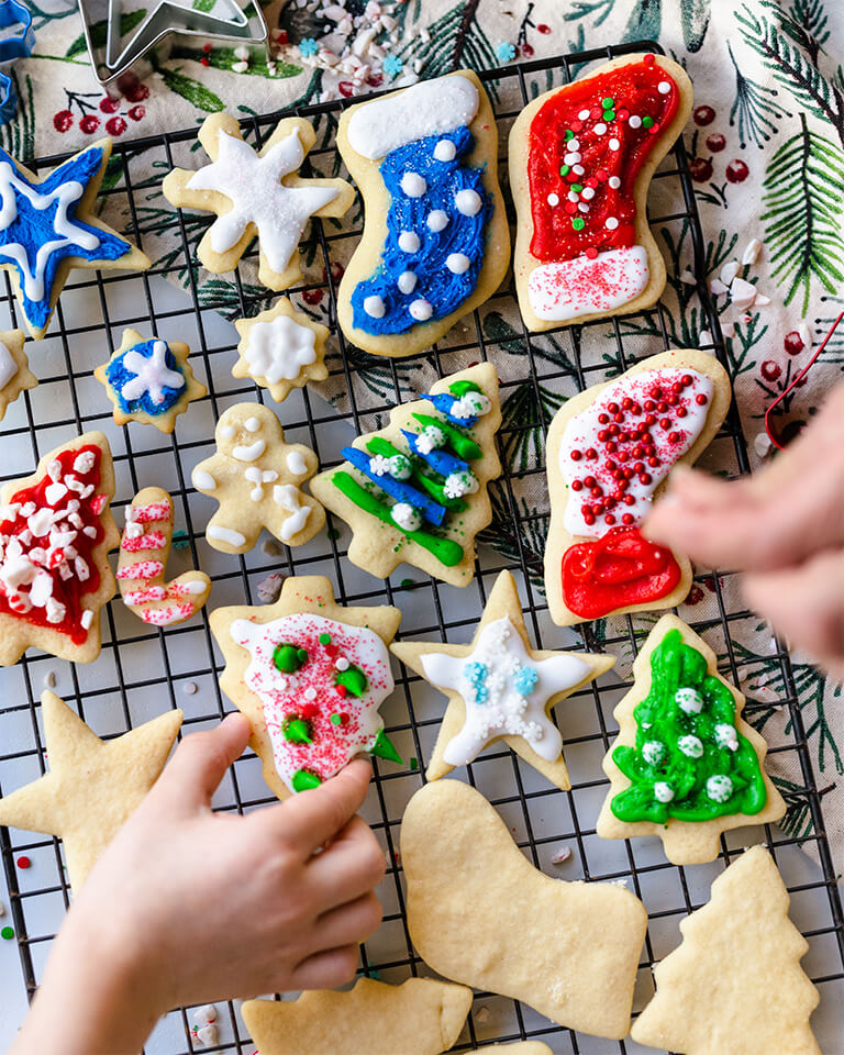 Holiday cookies being decorated on a cooling rack